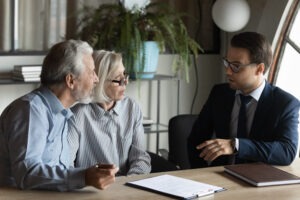 An investment fraud lawyer serving clients in Boston, sitting with his elderly clients, discussing their legal options.
