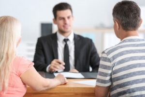 a middle-aged couple seated at a male attorney’s desk