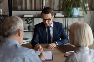 A lawyer sits across the desk from two clients who lost money to high-risk alternative investments.