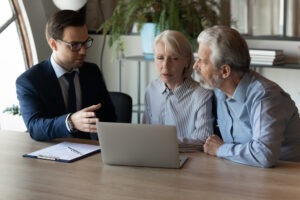 A financial advisor sits at a desk with an elderly couple and explains what options trading is.