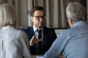 An investment fraud lawyer meeting with a senior couple and explaining the obligations of a stockbroker to their clients.