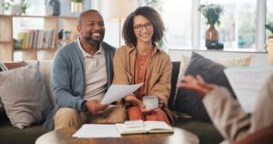 A life insurance premium financing scam lawyer talks to a mature couple sitting on a couch.