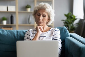 A woman sitting on her couch and wondering, “Is whole life insurance a scam?”