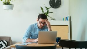 A stressed man uses a computer to look up what to do if a Crypto.com account is hacked.