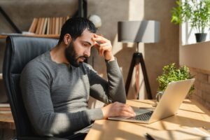 Man sits at computer desk and looks up what to do if your Kraken account gets hacked.