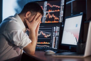 A frustrated man in front of a computer screen learns what a margin blowout is. 