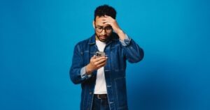 Person looking down at a phone and worried about what to do since their OKX account was hacked