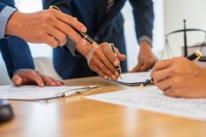 Three men stand over a desk with contracts and pens in hand, discussing whether AAA arbitration is binding.
