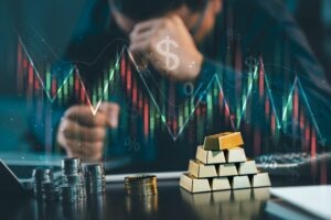 Stressed investor with gold bars and coins looking at a falling stock market chart