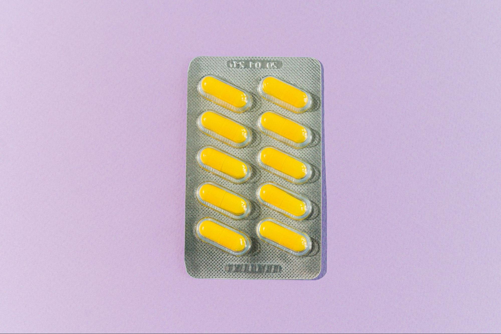 Blister pack of ten yellow capsules on a lilac background