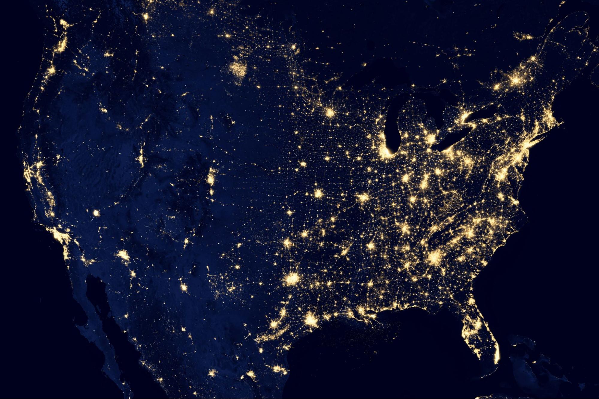 Satellite image of the United States at night showing city lights across the country