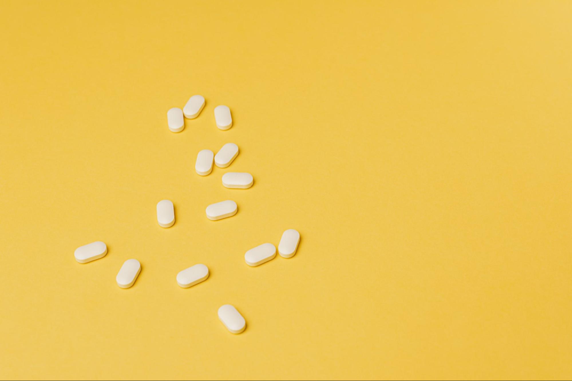 White oval tablets scattered across a yellow background